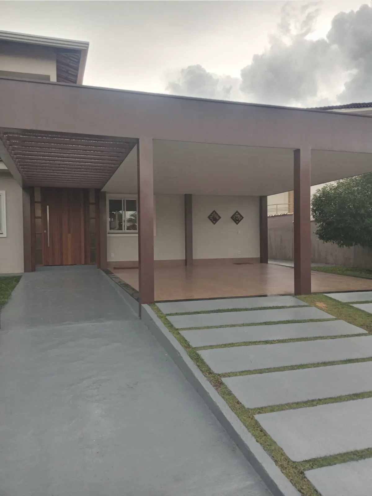 Fachada de casa com varanda coberta, pilares pintados e piso externo