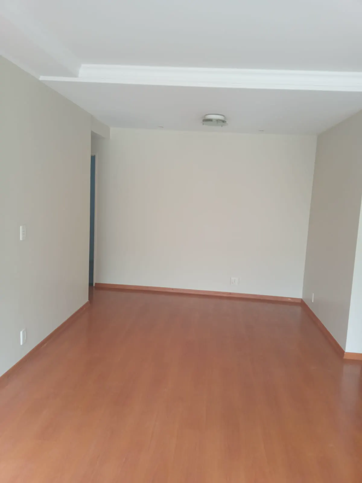Sala de apartamento vazia com paredes claras recém-pintadas e teto com sanca